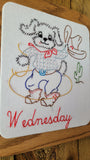 A square white embroidered patch featuring a cartoon dog dressed in western clothing with the word 'Wednesday' stitched in red script at the bottom, shown on a wooden surface.